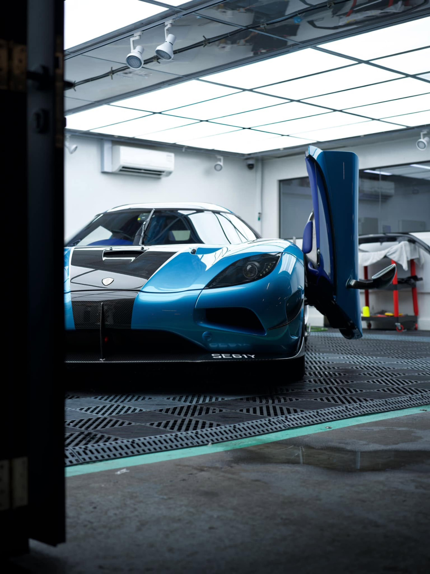 A blue Koenigsegg in the MintGroom studio with doors open under panel inspection lighting